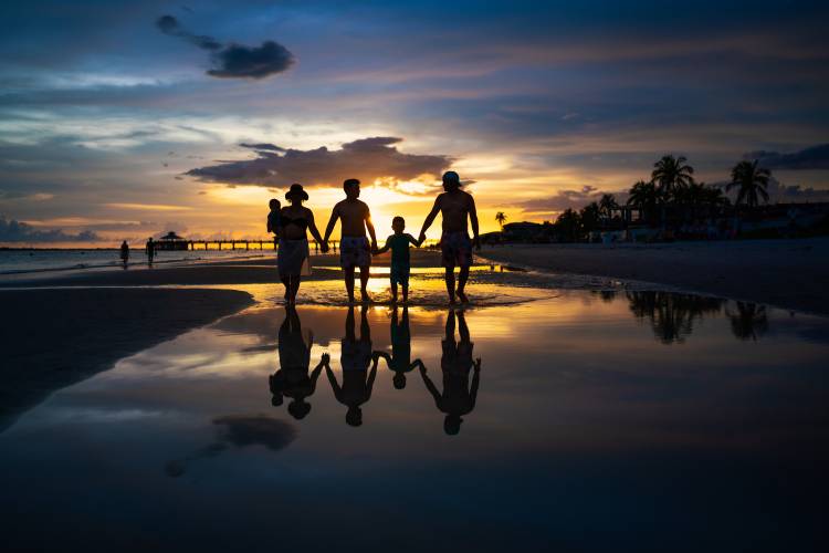 family walking on beach at sunset
