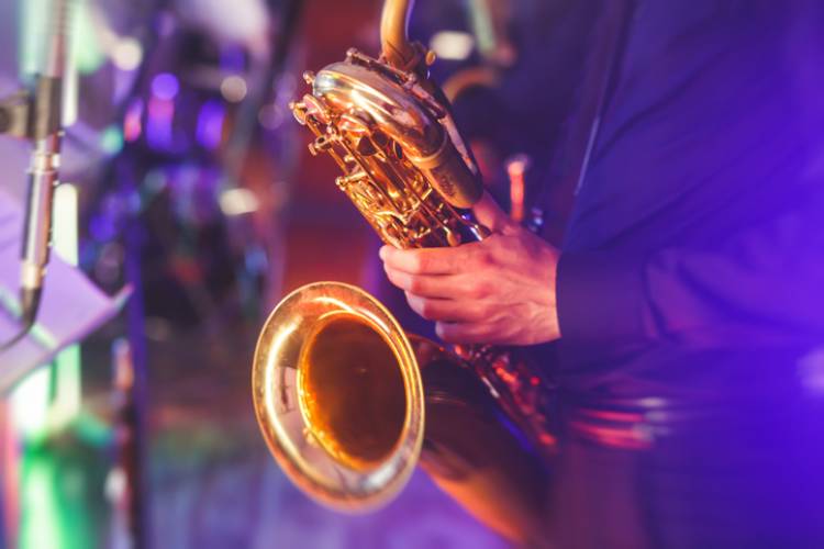 Concert view of a saxophone player with musical jazz band in the background