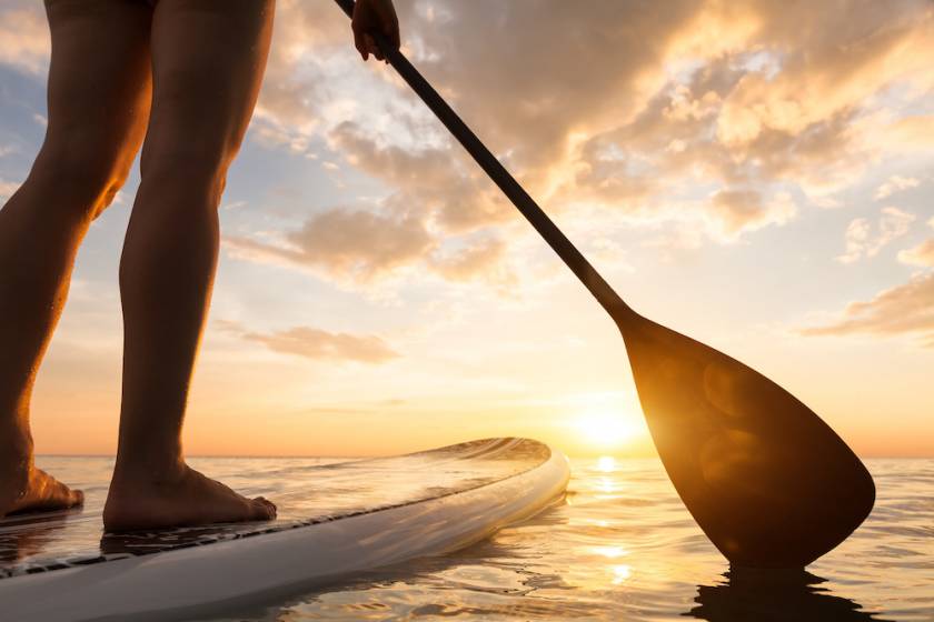 just the legs of a person on a stand up paddleboard as they float